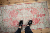 Vintage distressed Oushak rug's soft raspberry and celadon colors shown for scale.