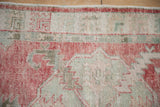 The distressed, low-pile texture of a vintage Oushak rug in pale raspberry and dusty celadon.