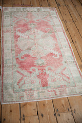 Angled perspective of a vintage Oushak runner with a soft raspberry and celadon design.