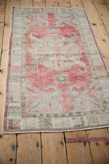 The soft, abrashed field of a distressed vintage Oushak rug in raspberry and celadon.