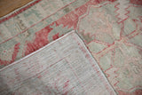 Corner of a distressed Oushak rug folded to reveal its hand-knotted back weave.