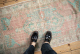 Softly faded colors and low-pile texture of a distressed vintage Oushak rug runner.