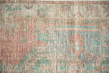 Evenly worn low pile of a distressed Oushak rug with faded pink and pale turquoise motifs.