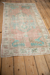 Angled view of a distressed Oushak runner highlighting its time-softened pink and turquoise pattern.