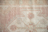 Distressed Oushak rug pile detail, with dusty rose, ivory, and faint silver geometric patterns.