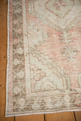 Distressed Oushak rug's side, showing worn rose and bronze floral border motifs.