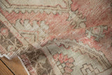 Worn pile texture of a distressed Oushak rug in dusty rose and cream hues.