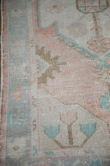 Distressed vintage Oushak rug close-up, soft dusty rose, pale turquoise, and coffee brown patterns with worn pile.