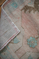 Distressed Oushak rug texture with worn dusty rose, pale turquoise pile, and exposed foundation.