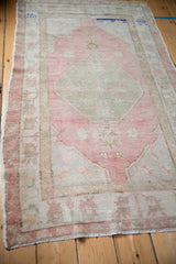 Faded pink and beige distressed Oushak rug with unique cobalt blue accents at one end.