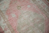 Evenly worn hand-knotted pile showing the faded pink and sand colored texture.