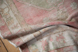 Soft, draped texture of a distressed vintage Oushak rug in faded raspberry and sand tones.