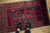 Vintage Oushak rug with distressed cochineal red and navy pile shown underfoot for scale.