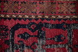Detailed view of a distressed rug's heavy abrashes and varied dye lots in red and navy.