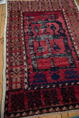 Corner view of a vintage Oushak rug shows cochineal red and navy patterns with heavy, textural abrashes.