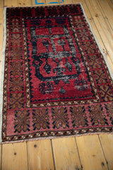Angled view of a vintage distressed Oushak rug with heavy abrashes over its red and navy design.