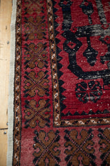A close view of the distressed corner on a vintage Oushak, showing the wide brown border and red pile.