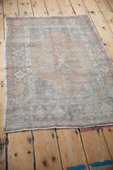 Distressed vintage Oushak rug from an angle, highlighting its worn texture and central medallion design.