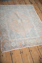 Angled perspective of a vintage Oushak rug highlighting its softly worn low pile and geometric pattern.