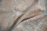 The low, even pile of a distressed Oushak rug in sandalwood, silver, and tangerine hues.