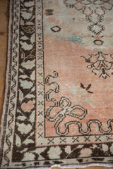 Intricate vine border on vintage distressed Oushak runner with faint foundation and cantaloupe tones.
