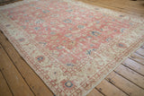 Distressed pile texture of a vintage Sparta carpet, showing a machine bound side with blush, ivory, and blue florals.