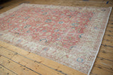 Distressed Sparta carpet detail, faded dusty blush and ivory floral motifs, worn pile, machine bound edge.