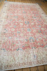 Distressed Sparta carpet detail with dusty blush field, blue floral blossoms, and worn beige palmettes.