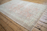 Distressed vintage Sparta carpet corner, showing faded dusty blush and silver floral patterns.