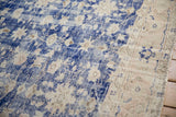 Distressed cobalt blue field and faded floral motifs with a machine-bound edge.