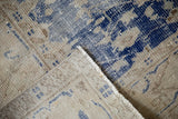 Distressed Oushak rug, worn cobalt blue patterns, exposed foundation, and machine bound edge.
