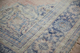 Distressed vintage Oushak rug texture with worn cobalt blue and dusty pink stylized motifs on beige.