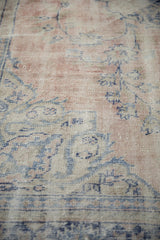 Distressed vintage Oushak rug pile texture with faded rose and soft blue hues.