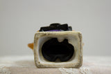 The ripped black rubber plug at the base of the vintage piggy bank.