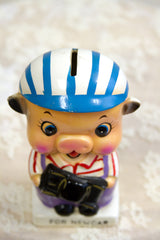 Coin slot on the vintage piggy bank's glossy, blue and white striped helmet.
