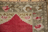 Distressed Oushak rug showing stepped red mehrab and blush floral border details.