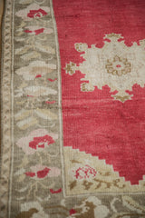 Hand-knotted texture of a distressed vintage Oushak rug's cherry red field and floral border.