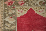 Stepped cherry red mehrab with blush floral patterns on a distressed Oushak rug.
