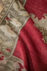 Distressed Oushak rug texture with rich cherry red pile and oxidized silver geometric patterns.