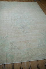 Angled view across a distressed Oushak rug showing its soft, low-pile texture and gentle sheen.