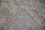 Folded corner of a distressed Oushak carpet showing its low pile and hand-knotted back.