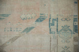 Evenly worn pile of a distressed Oushak rug with visible knot heads in pale rose and dusty teal.
