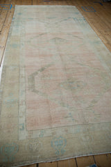 Angled view down the distressed Oushak runner, highlighting its pale rose and sand field.
