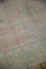 Close view of the distressed Oushak's even wear, showing low pile and a small, neat patch.
