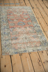 Distressed vintage Oushak rug detail: worn dusty blush pile and patterned cobalt border.
