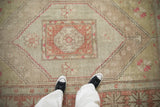 Distressed Oushak hand knotted rug: hexagonal medallion, pinwheel florals in sage, pale red.