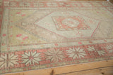 Distressed vintage Oushak rug corner, pale brick red starburst border, sage green stepped field with abrashes.