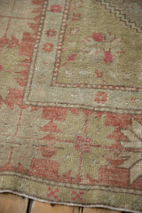 Vintage distressed Oushak rug detail with soft green and muted brick red patterns.