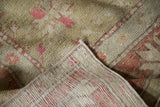 Distressed vintage Oushak carpet's hand-knotted pile and striped woven foundation.