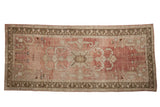 Distressed vintage Oushak rug runner with faded cochineal red abrashed field and oversize palmette medallion.